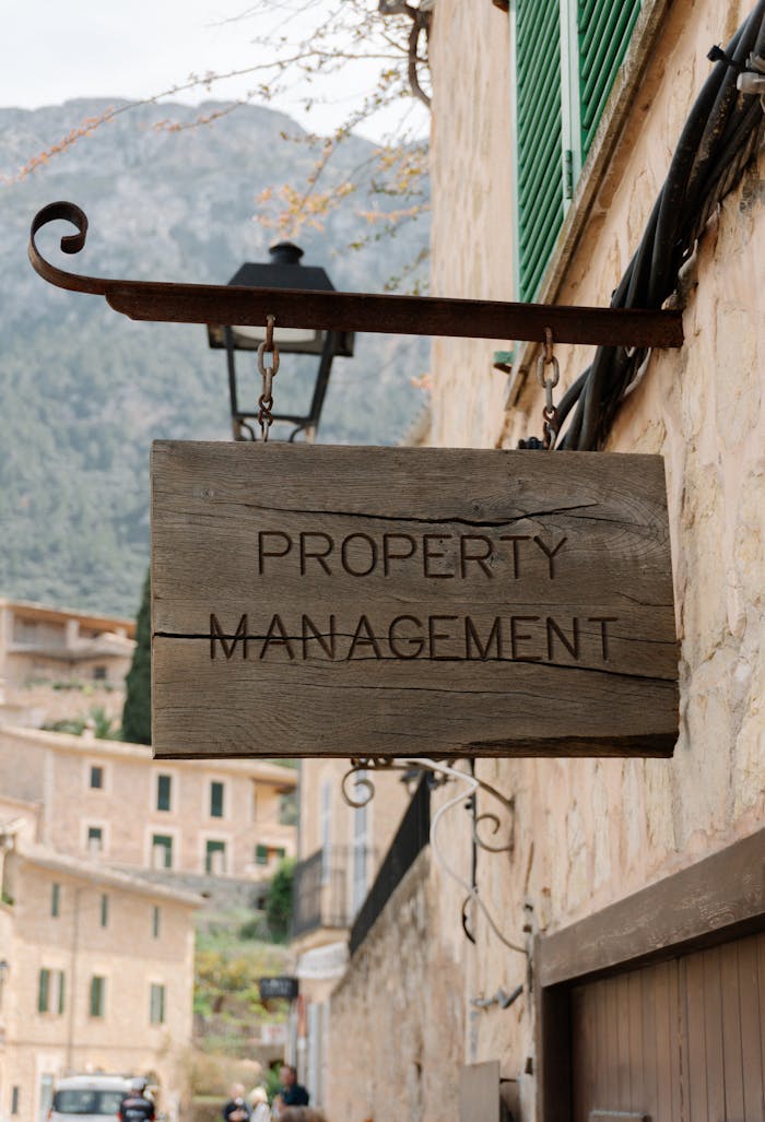 portfolio-04 Wooden property management sign in a picturesque European village, featuring charming architecture.